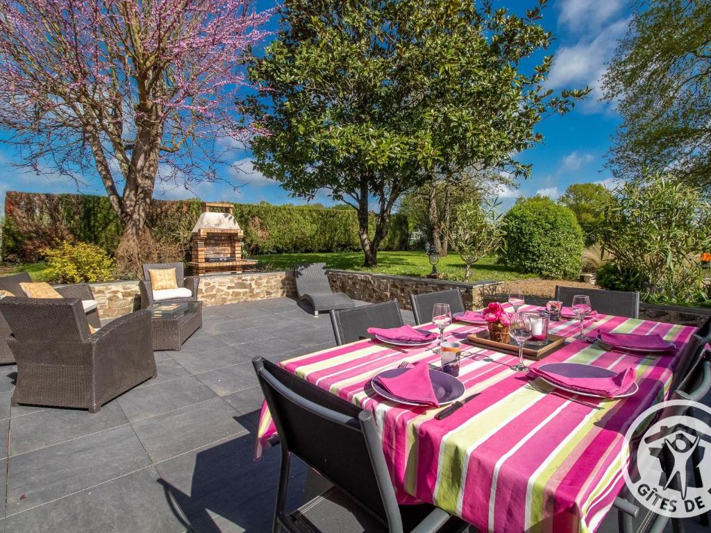 a table with a pink and white table cloth on a patio at Gîte charmant avec jardin, proche activités nautiques - FR-1-622-75 in Morannes