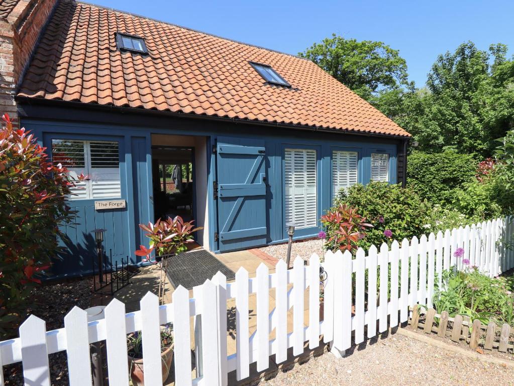ein blaues Haus mit einem weißen Gartenzaun in der Unterkunft The Forge in Grimsby