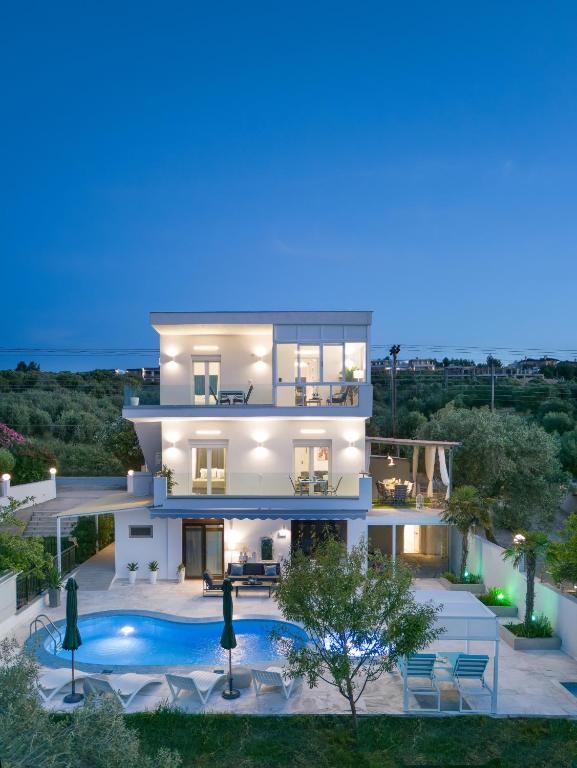 a villa with a swimming pool at night at Stork Apartments in Hanioti