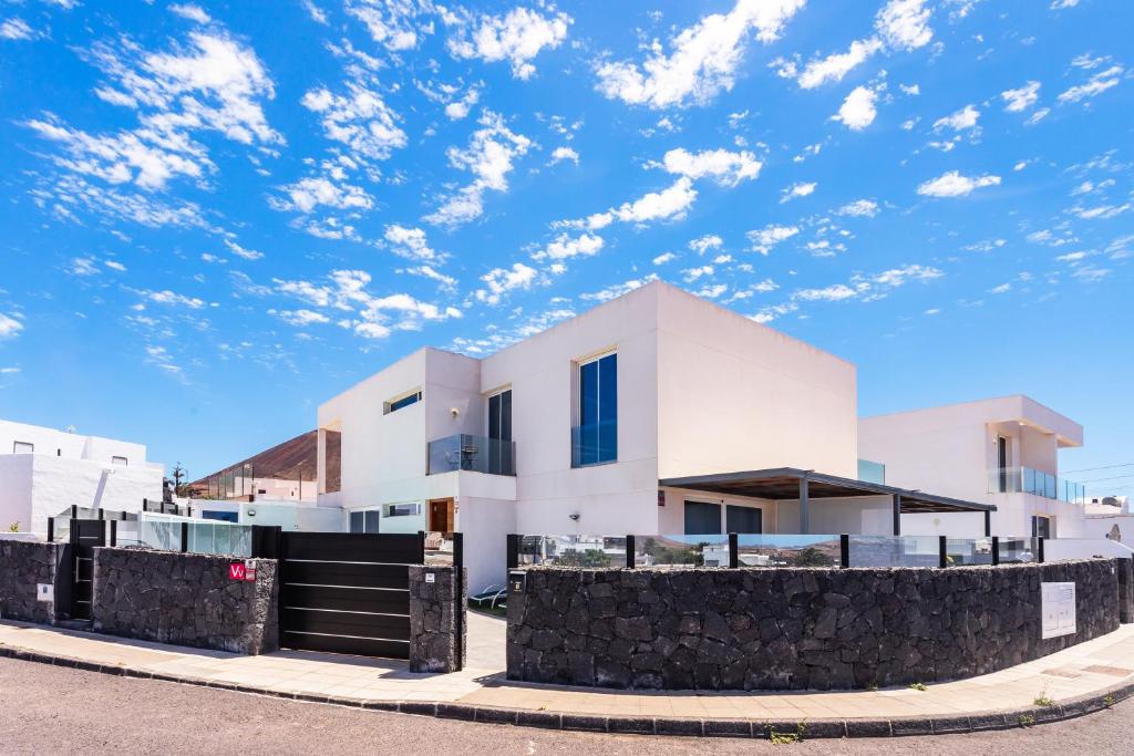 una casa blanca con un cielo azul con nubes en Casa Daniela Lanzarote piscina climatizada, barbacoa y wifi free, en Tahiche