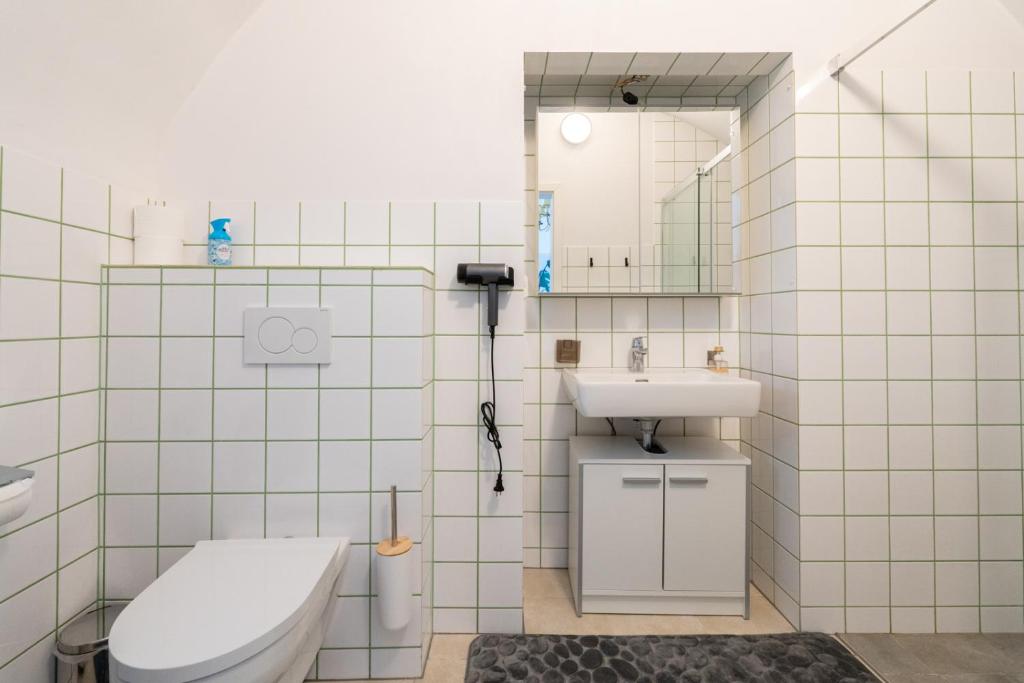 a white tiled bathroom with a toilet and a sink at Wachau Familienoase &#47; 60m² &#47; Gartenparadies in Mautern