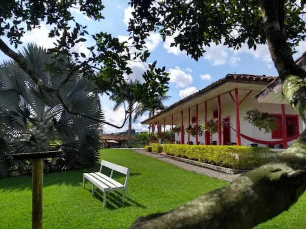 ławka siedząca w trawie przed budynkiem w obiekcie Finca Hotel Santana Campestre w mieście Quimbaya