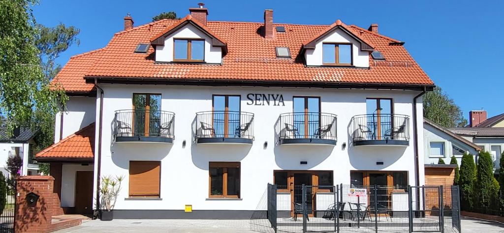 a white building with a red roof at Pensjonat Senya in Niechorze