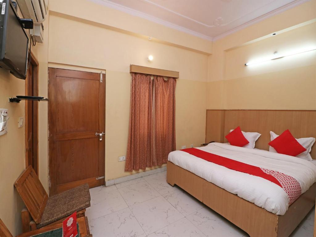 um quarto com uma cama grande e almofadas vermelhas em OYO 24103 AKBAR PALACE em Alīgarh