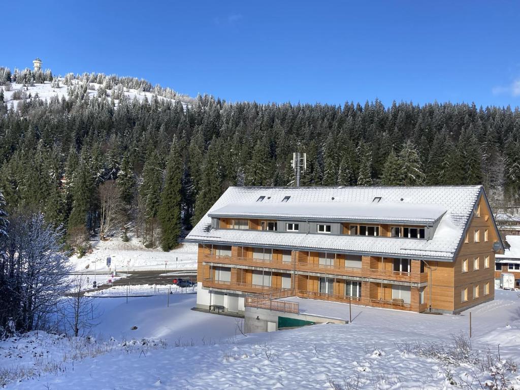a large wooden building in the snow with trees at Haus Wiesenquelle in Feldberg
