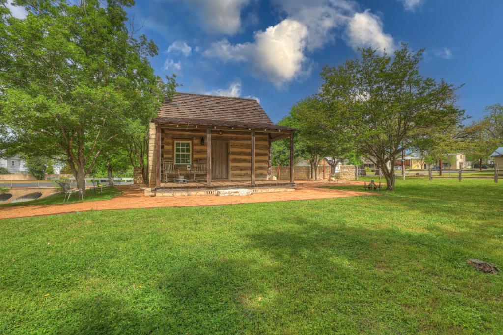 a log cabin in a field with trees at Town Creek Cabin Walk to Main St in Fredericksburg