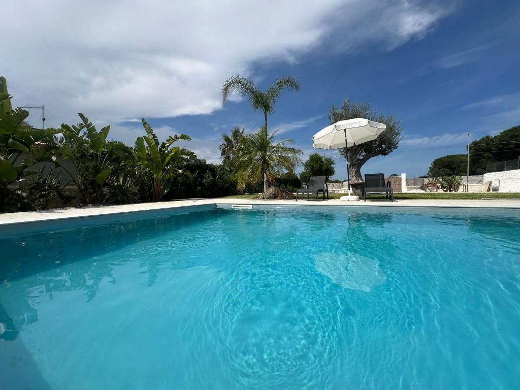 una gran piscina azul con sombrilla en Appartamenti - Villa Merilusi, en Fontane Bianche