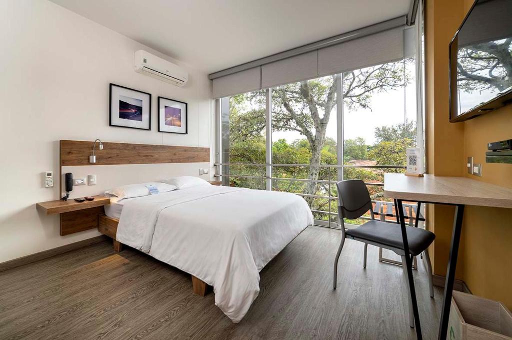 a bedroom with a bed and a desk and a window at Hotel Park 85 in Cali