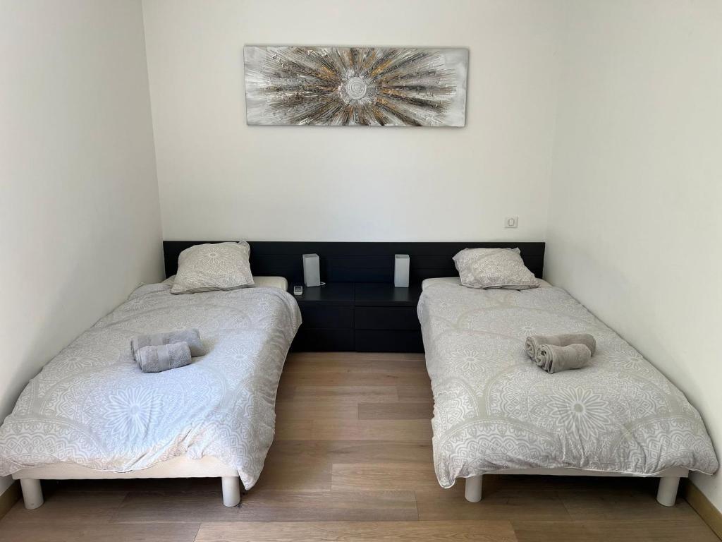 twee bedden in een kamer met witte muren bij APPART Tropez 1 in Saint-Tropez