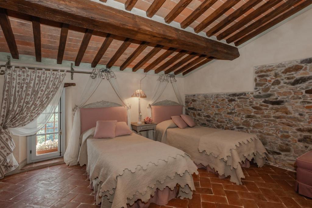 sypialnia z 2 łóżkami i kamienną ścianą w obiekcie Villa sii felice w mieście Buti