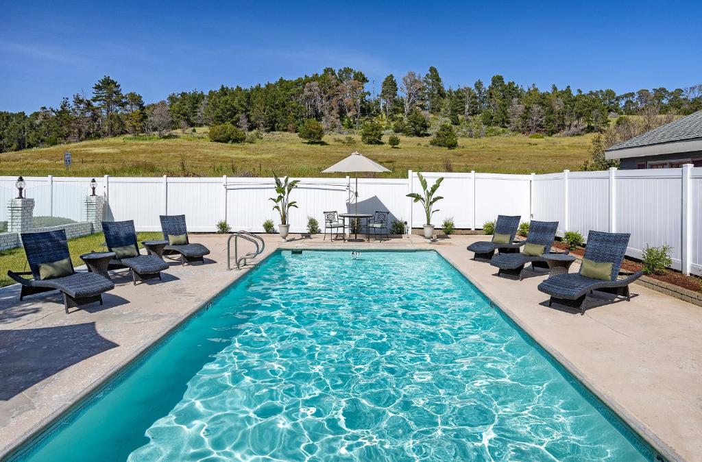a swimming pool with chaises and chairs in a backyard at Fireside Inn on Moonstone Beach in Cambria