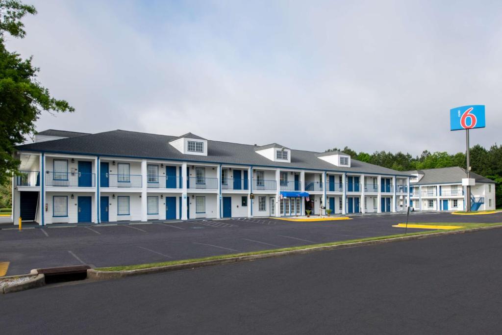 ein großes weißes Gebäude mit blauen Fenstern und einem Parkplatz in der Unterkunft Motel 6 Macon, GA I 475 in Macon