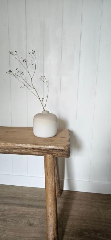 a white vase sitting on top of a wooden table at Les Cocons d AleXan Le Chalet balnéo aromathérapie in Quinssaines