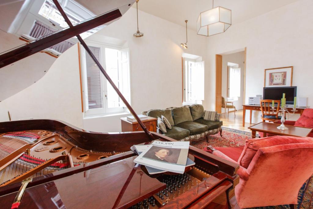 a living room with a piano and a couch at Habitat's Navona 4BR Apartment in Rome