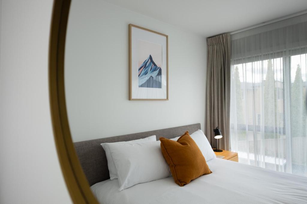 a bedroom with a bed with white pillows and a window at Alpine Junction Townhouse Apartments, Lodge & Hotel in Wanaka