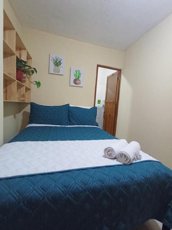 a bedroom with a blue bed with towels on it at Hotel Cuencano Hogar in Cuenca