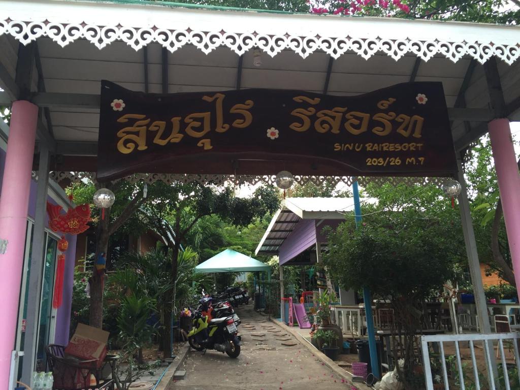 a banner hanging from a building with a motorcycle parked in front at Sin U Rai Resort in Ko Larn
