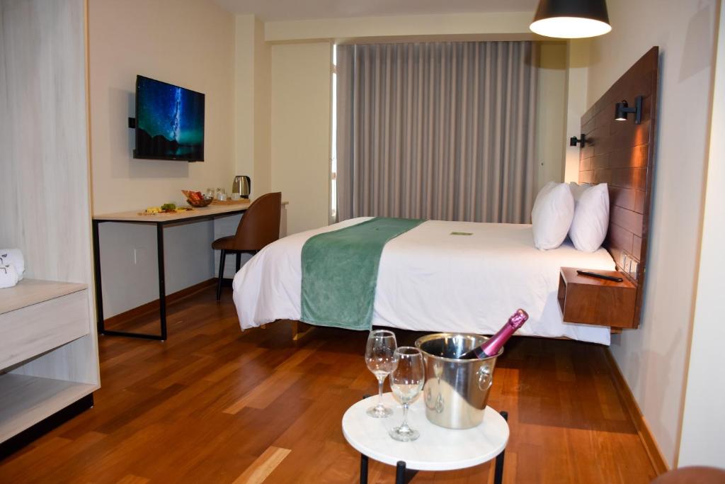 ein Hotelzimmer mit einem Bett und einem Tisch mit Weingläsern in der Unterkunft Muña Hotel Andahuaylas in Andahuaylas