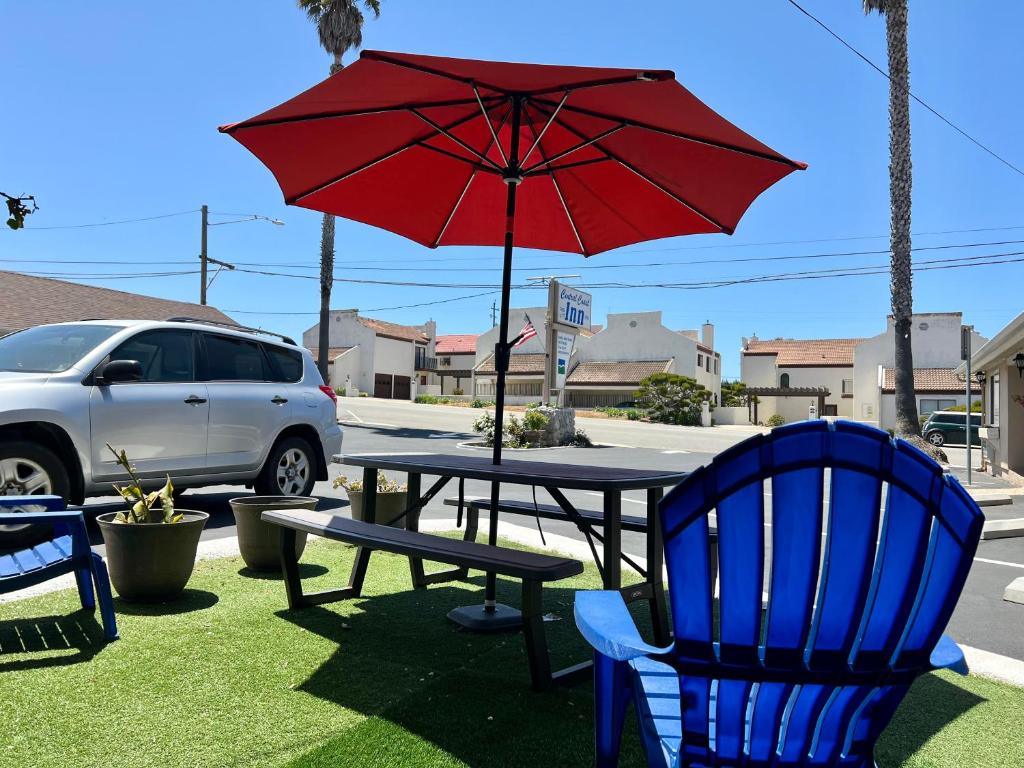 a picnic table with a red umbrella and chairs at Central Coast Inn Cayucos in Cayucos