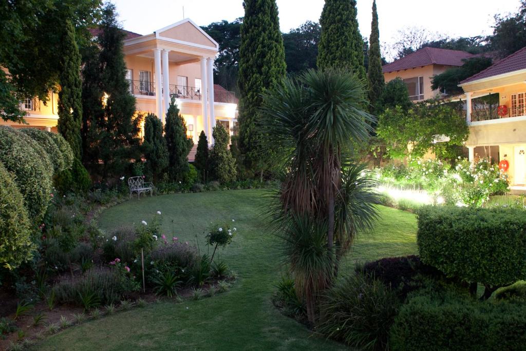 a garden in front of a house with a palm tree at Little Tuscany Boutique Hotel in Johannesburg