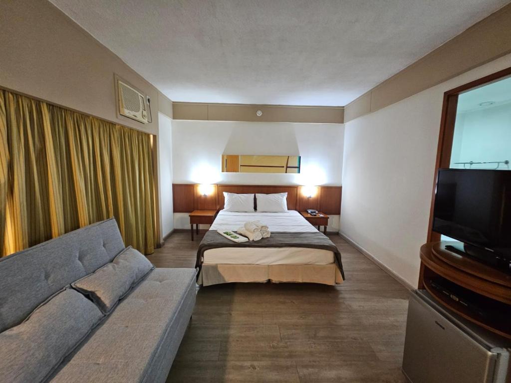 サンパウロにあるFlat Borges Lagoa Vl Mariana Ibirapuera com garagem UH1007のベッドとソファ付きのホテルルーム