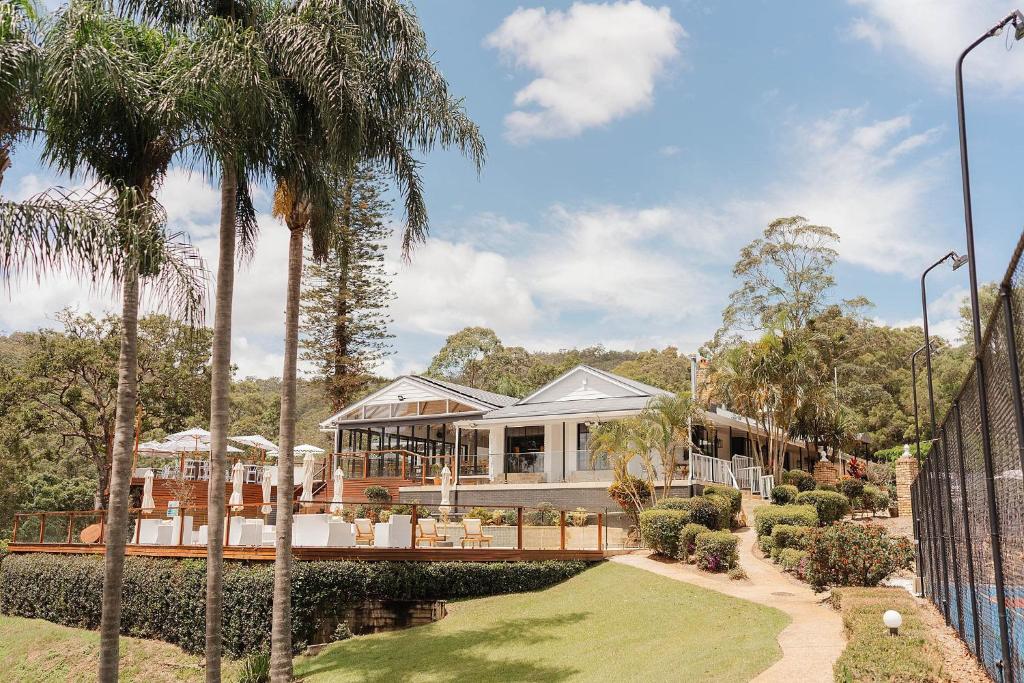 uma casa com palmeiras em frente em Austinvilla Estate em Mudgeeraba