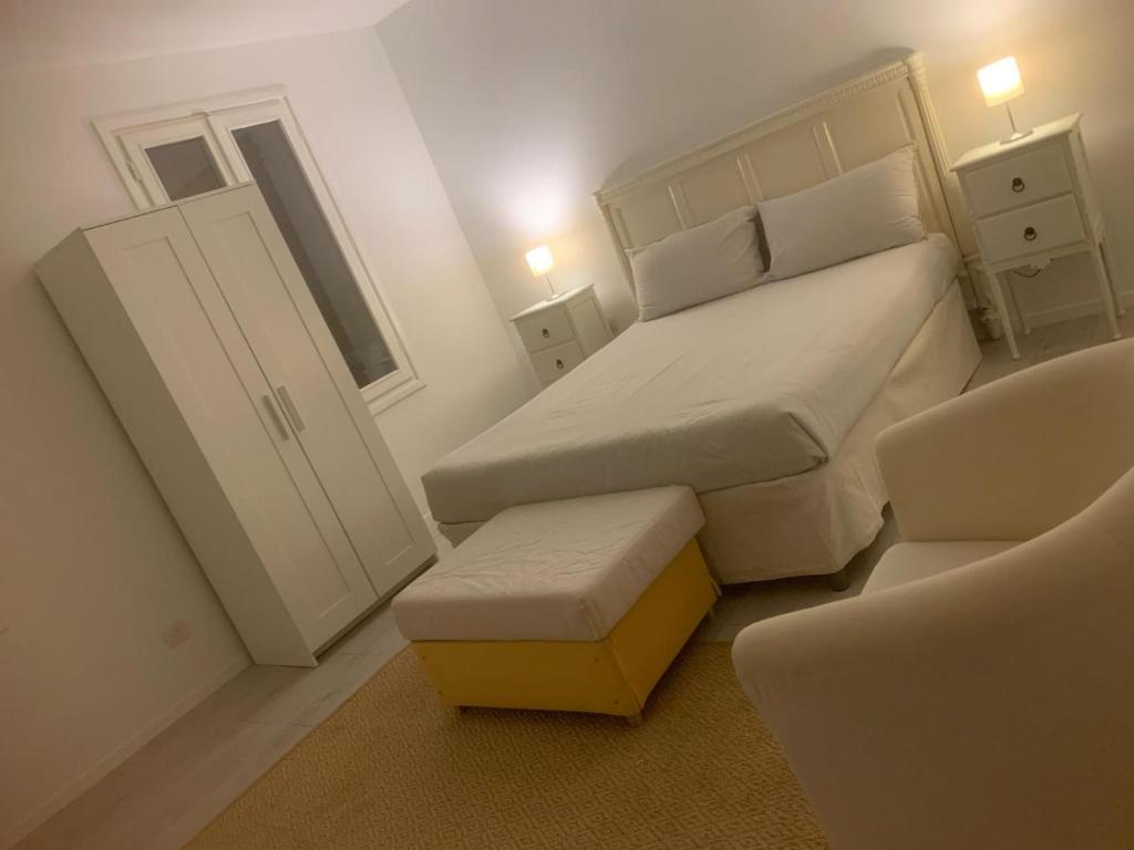 Dormitorio blanco pequeño con cama y taburete en Via Angarano 123, en Bassano del Grappa