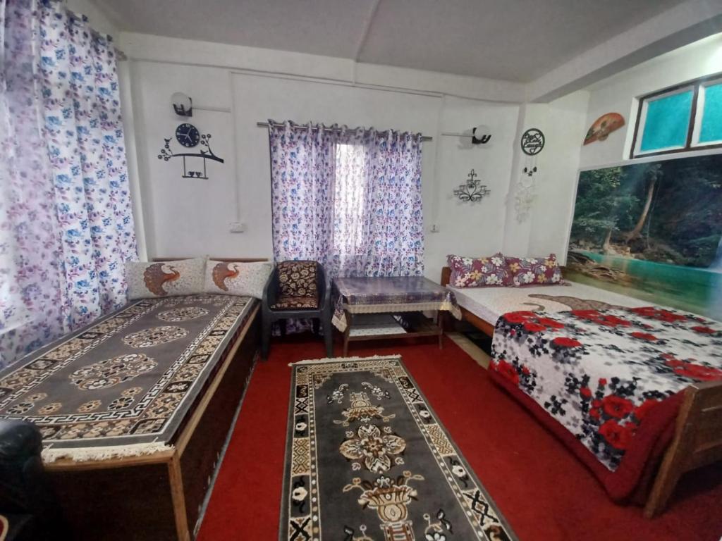 een slaapkamer met 2 bedden en een bank en een tafel bij Moktan Home Stay 4 in Kalimpong
