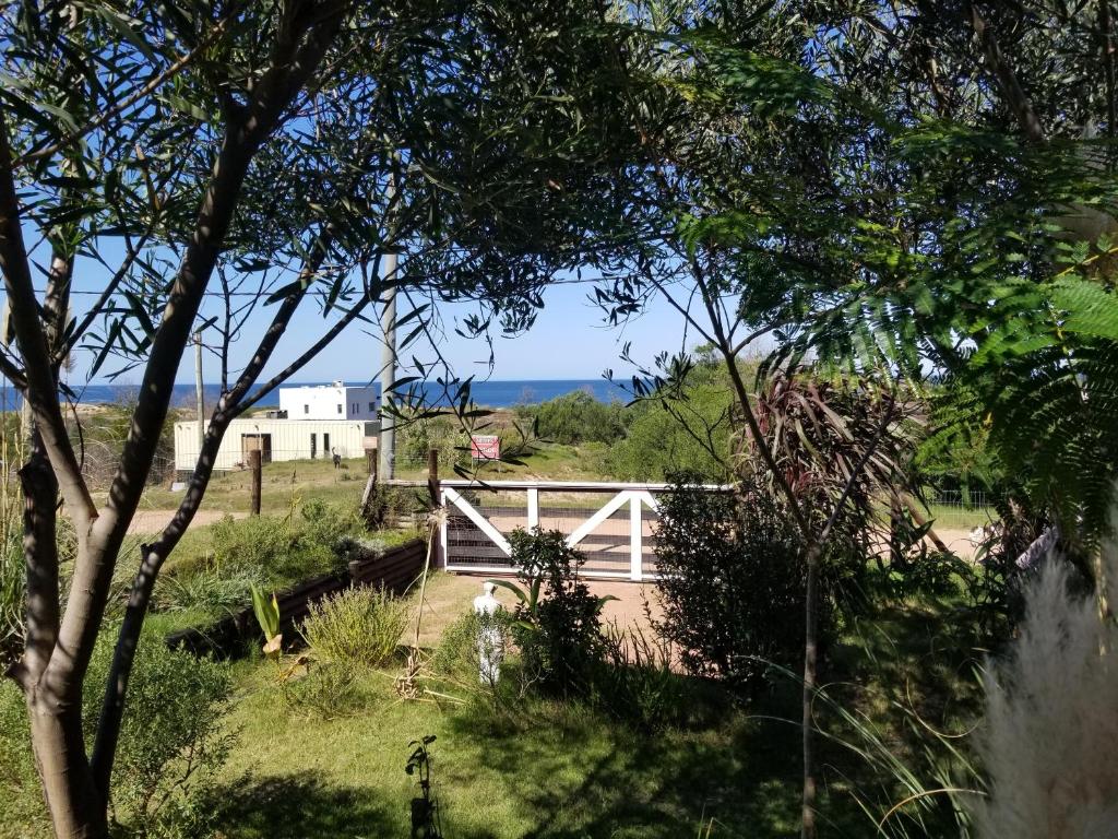 un portail blanc dans un champ avec l'océan en arrière-plan dans l'établissement Casita Picaflor, à Punta del Este