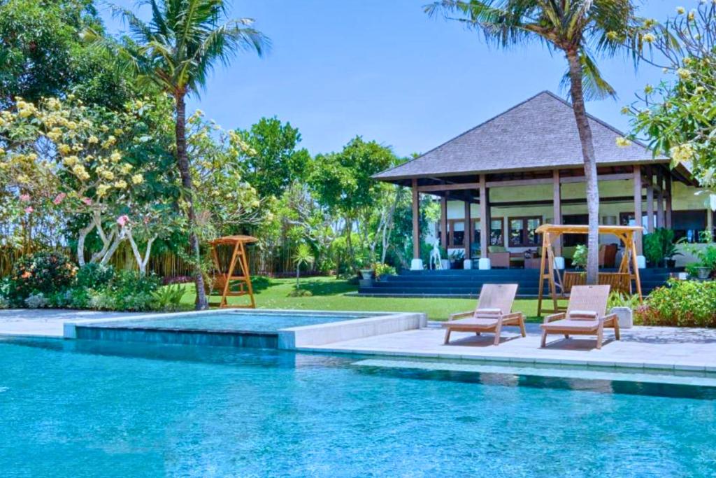 a swimming pool with two chairs and a house at Leah 6 BR Private Pool Villa JU26 in Ketewel