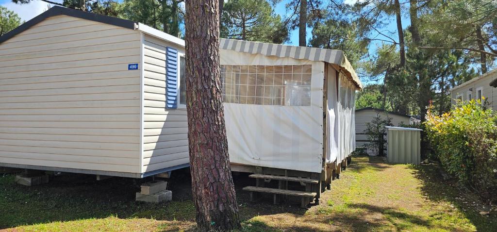 a small house sitting next to a tree at Mobil home La palmyre 8 Pers in Les Mathes