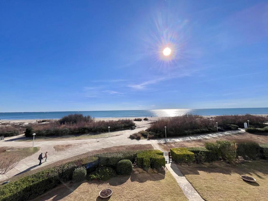 une personne marchant sur un trottoir près de l'océan dans l'établissement Appartement en bord de plage avec garage - FR-1-716-39, à La Grande Motte
