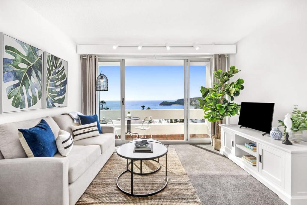 uma sala de estar com um sofá, uma televisão e uma mesa em Stunning Ocean Views With Manly At Your Doorstep em Sydney