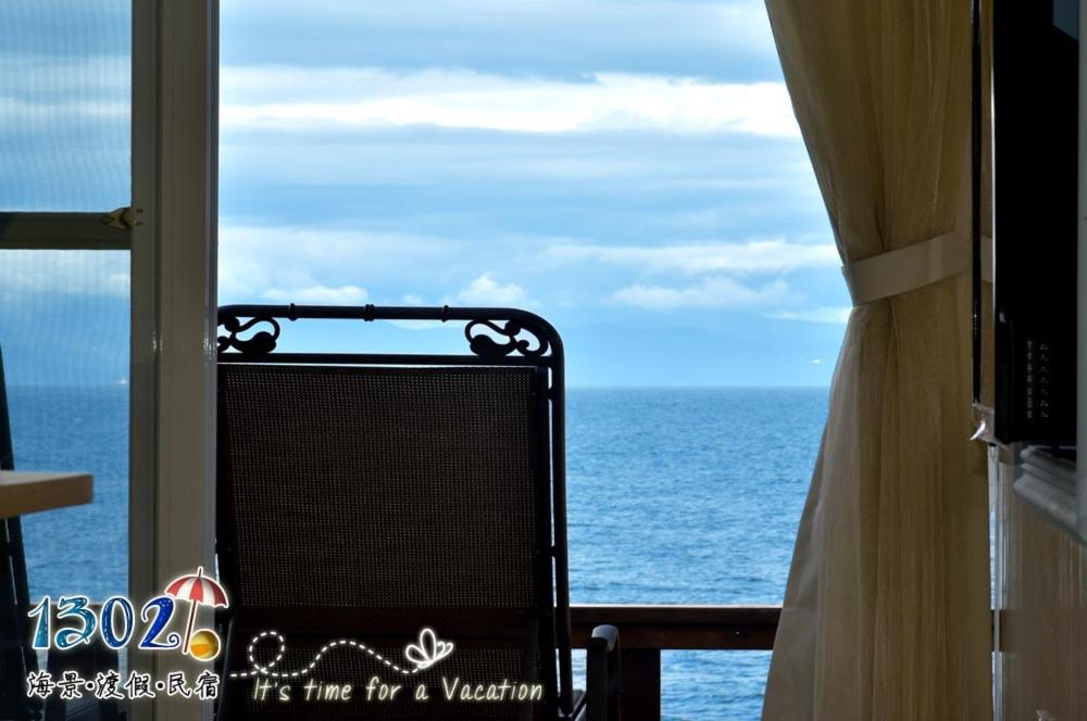 una silla sentada en un balcón con vistas al océano en 1302海景民宿, en Xiaoliuqiu