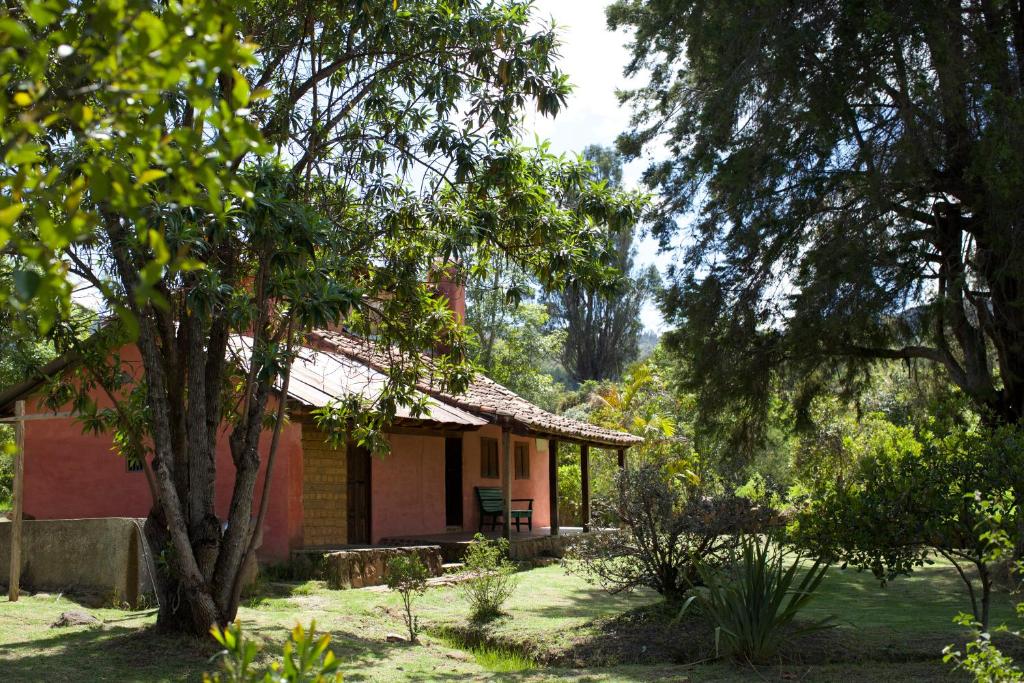 a house in the middle of a yard with trees at Hotel Ráquira Silvestre Lodge in Tinjacá