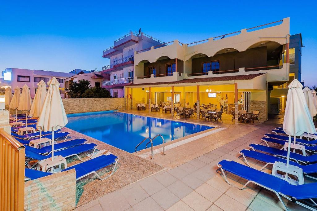 ein Pool mit Liegestühlen und Sonnenschirmen neben einem Gebäude in der Unterkunft Esmeralda Hotel in Kremasti