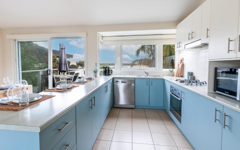 a large kitchen with blue cabinets and windows at 'The Grove' Family Home By The Beach in Ocean Grove