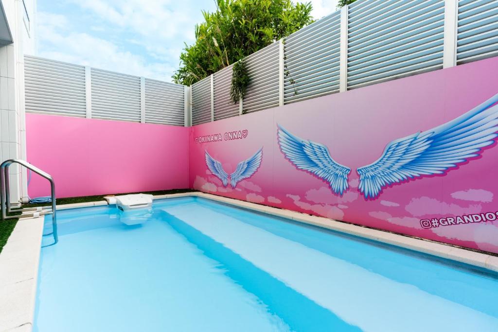 une piscine avec des ailes peintes sur le côté d'un bâtiment dans l'établissement Grandioso Okinawa Pool Villa Onna 9 - Vacation STAY 90315v, à Tancha