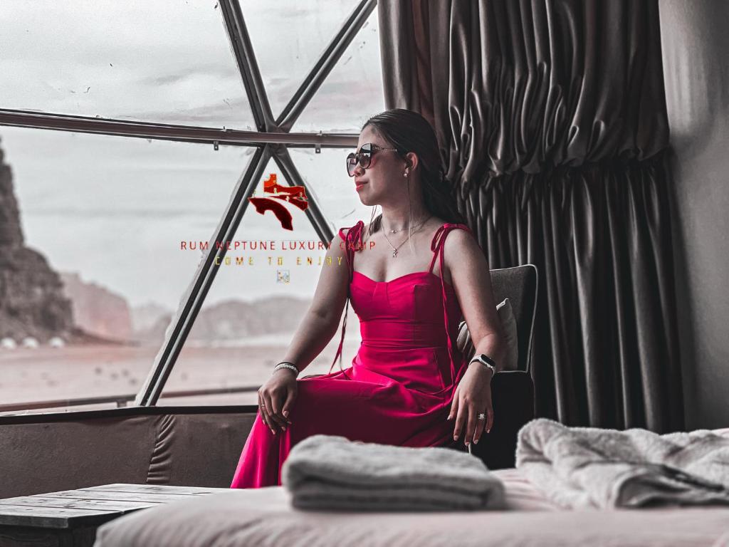 瓦迪拉姆的住宿－RUM NEPTUNE lUXURY CAMP，坐在窗边的红色衣服上的女人