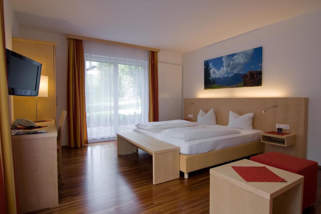 1 dormitorio con 1 cama blanca y TV en Austria Classic Hotel Heiligkreuz, en Hall in Tirol