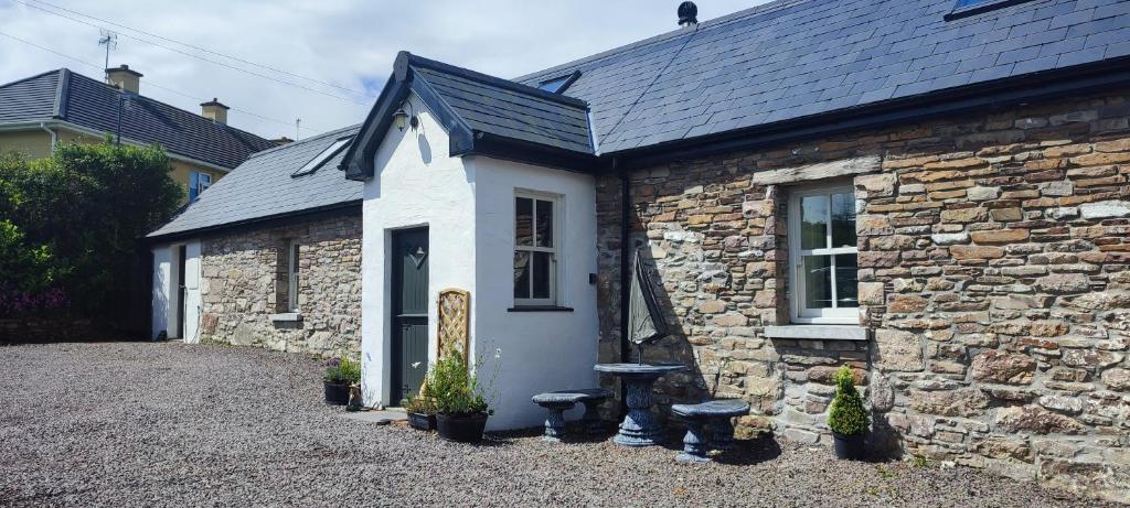 un pequeño edificio de piedra con un banco delante en The Old House at Belfield, en Tralee