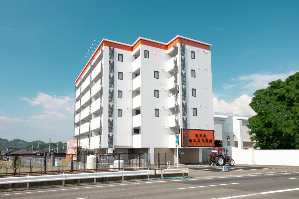 松山的住宿－Hotel Taiyo Nouen Furumitsu，白色的建筑,在道路的一边有红色的屋顶