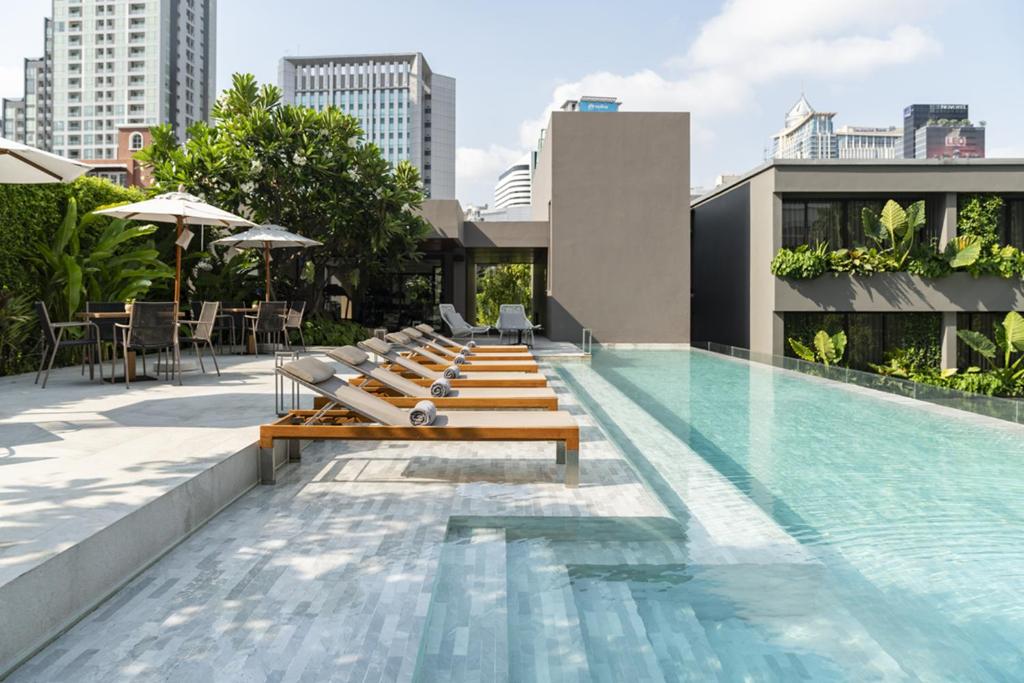 a swimming pool with benches on the side of a building at Ad Lib Hotel Bangkok in Bangkok