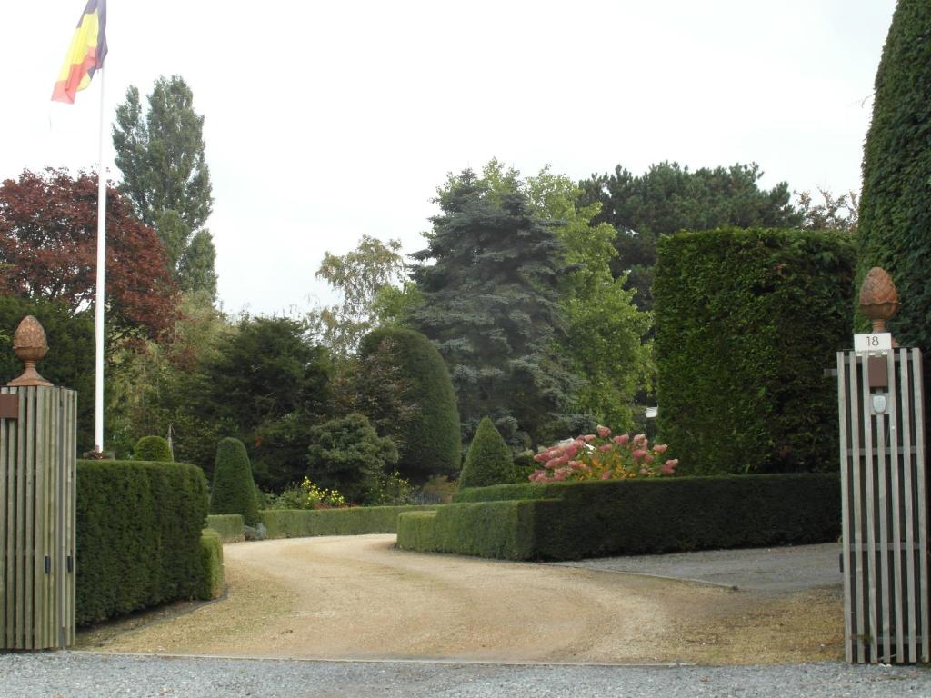 een tuin met struiken en heggen en een poort bij B&B Summergem in Zomergem 
