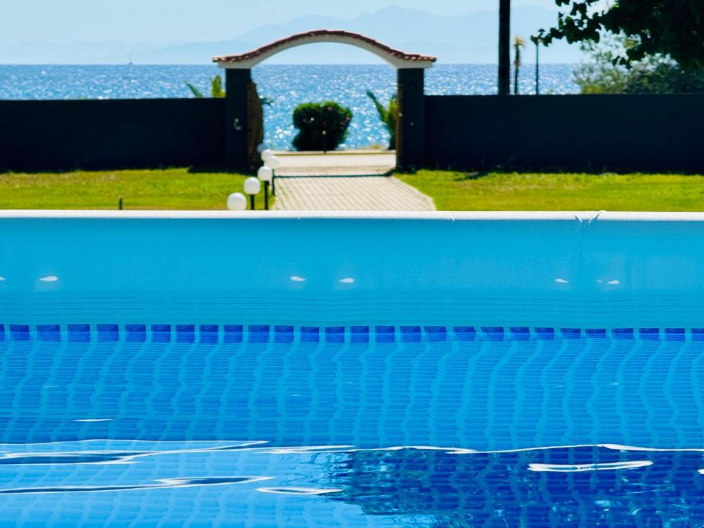 a blue swimming pool with an arch and the ocean at Gazonia Family Estate in Skala Kefalonias