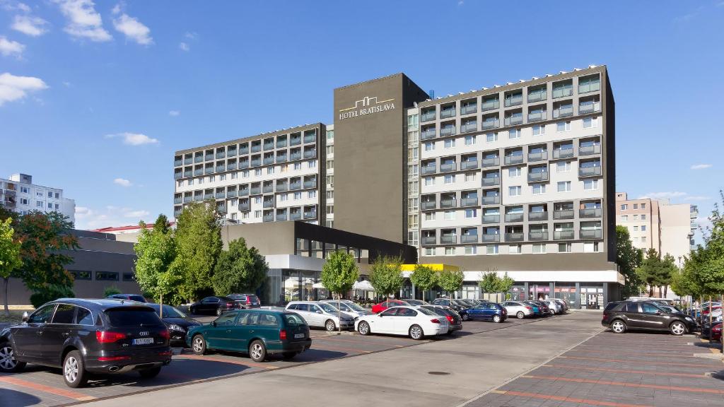 un estacionamiento con autos estacionados frente a un edificio en Hotel Bratislava en Bratislava