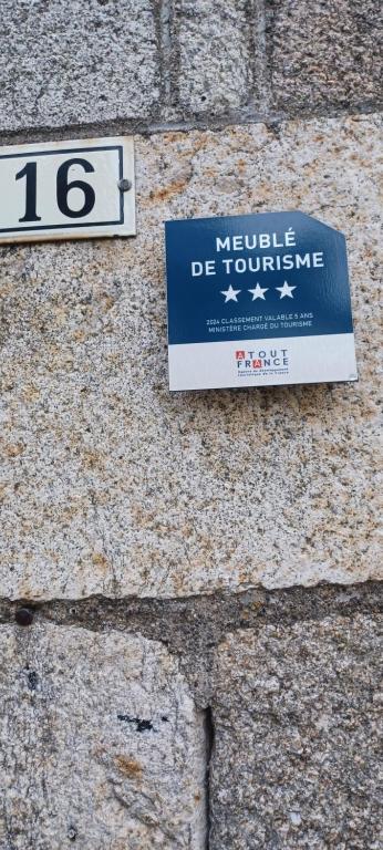 a sign on the side of a stone wall at Logis La P'tite Futée in Meymac
