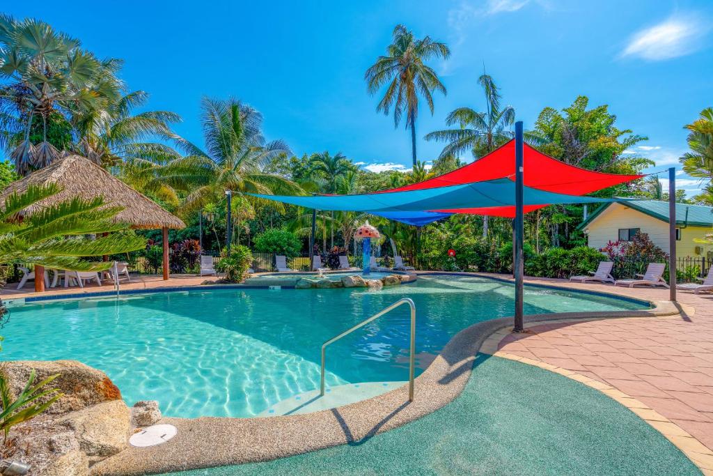 a swimming pool with a red and blue umbrella at BIG4 Tasman Holiday Parks - South Mission Beach in South Mission Beach