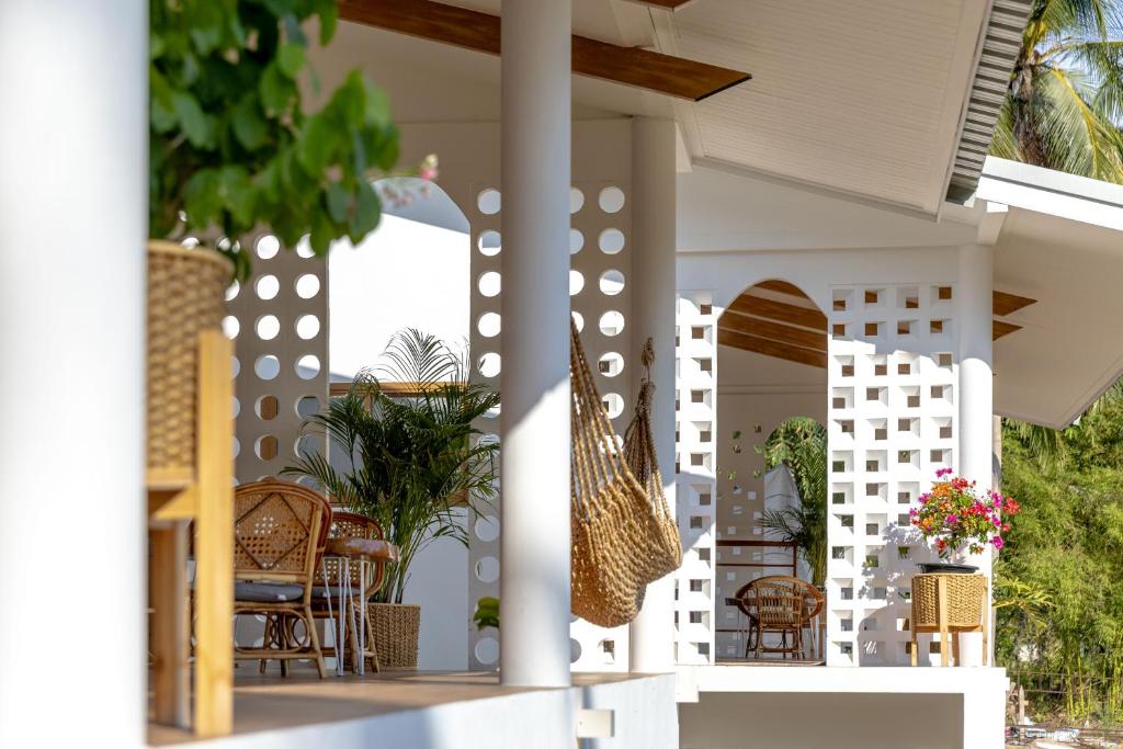 a white porch with chairs and a swing at Neverland in Ban Tai
