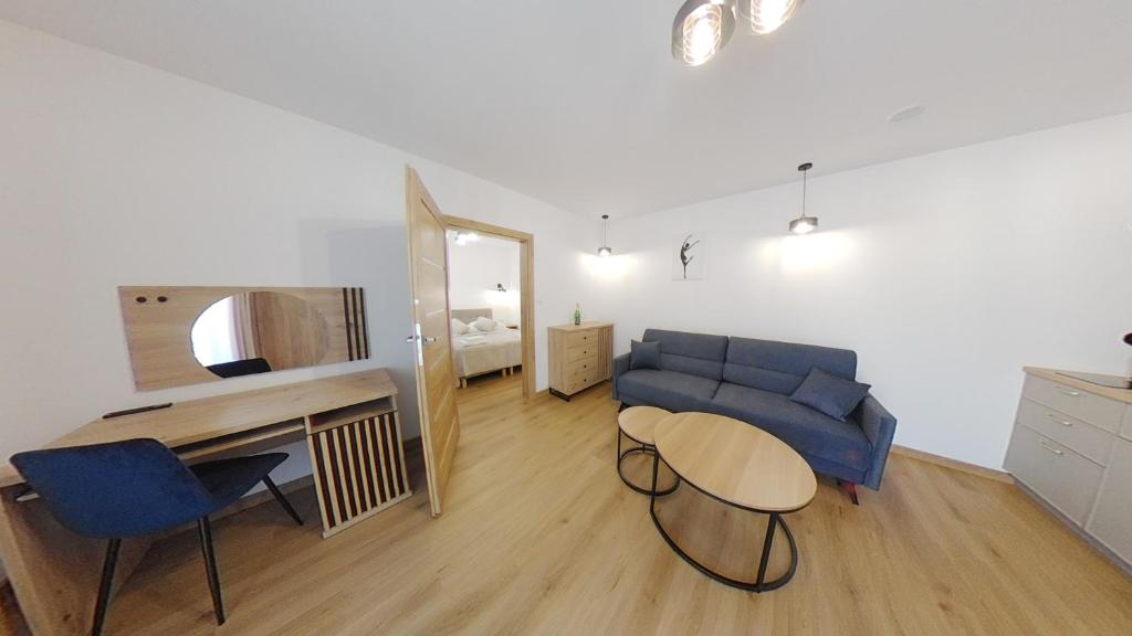salon z niebieską kanapą i stołem w obiekcie Apartament ARKA w mieście Jarosławiec